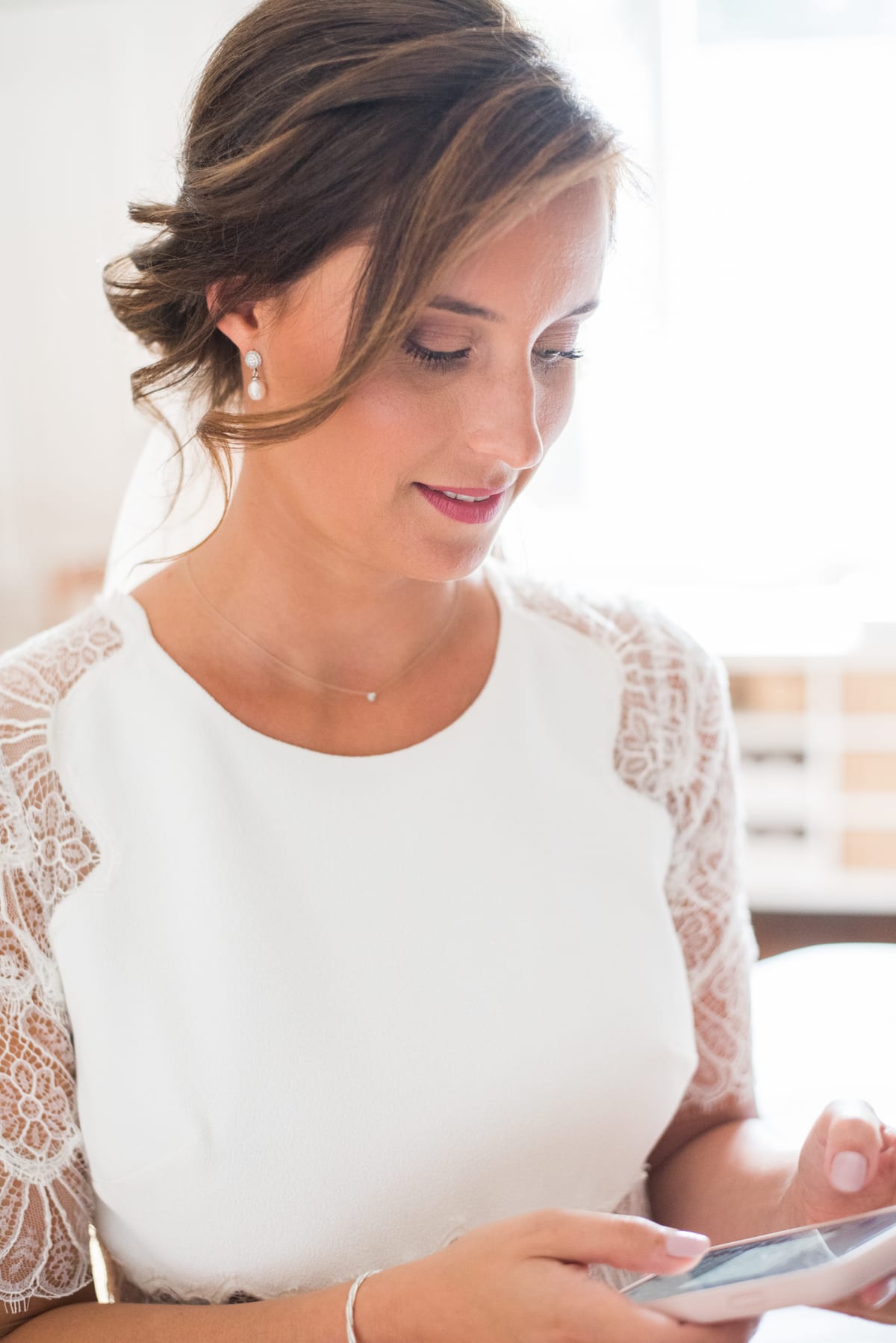 Mariée en robe de dentelle lisant un mot, lumière douce de fenêtre