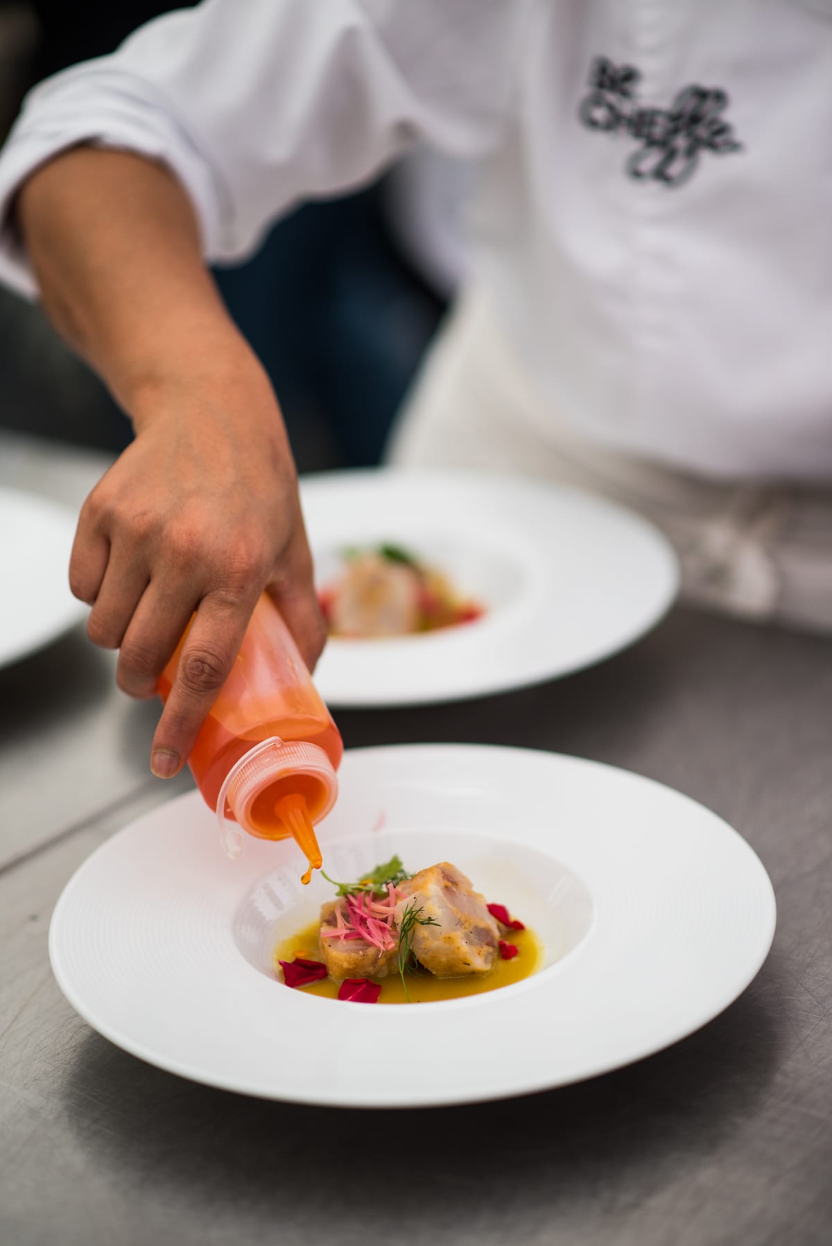 Cuisinier dressant une assiette à la pipette dans une cuisine professionnelle